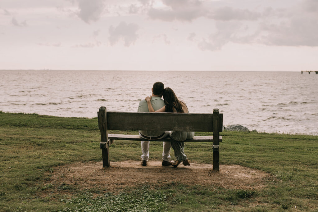 couple sitting on a bench gazing upon water on the pier in downtown Fairhope, AL