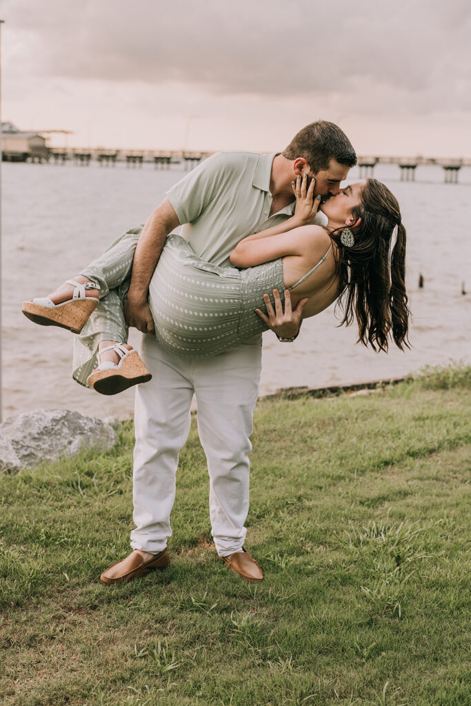 playful couple by the water on the pier in downtown Fairhope, AL