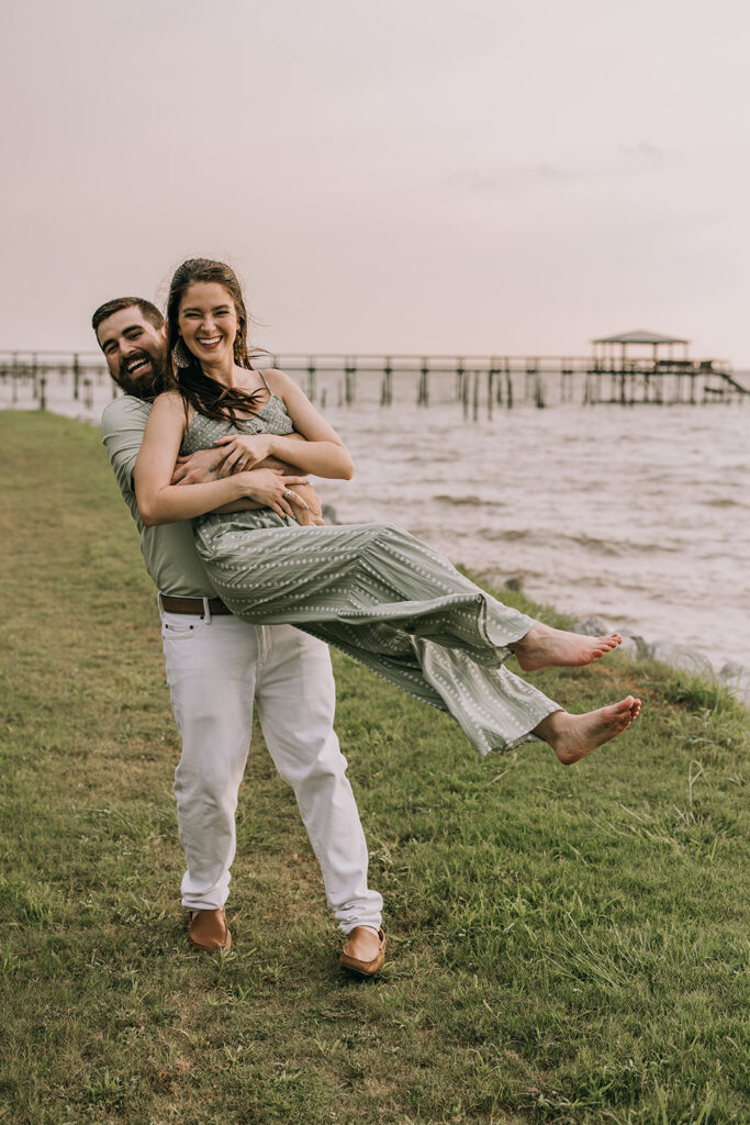 playful couple by the water on the pier in downtown Fairhope, AL