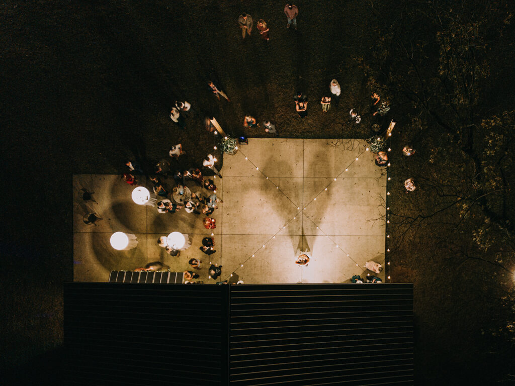 drone photo of bride and groom sharing their first dance outdoors, with their shadows forming a heart shape