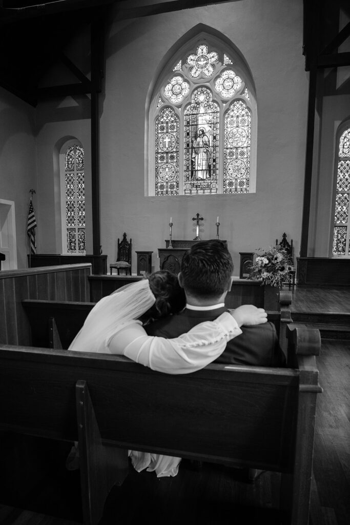 bride and groom sitting on the long benches at Old Christ Church in Pensacola, FL