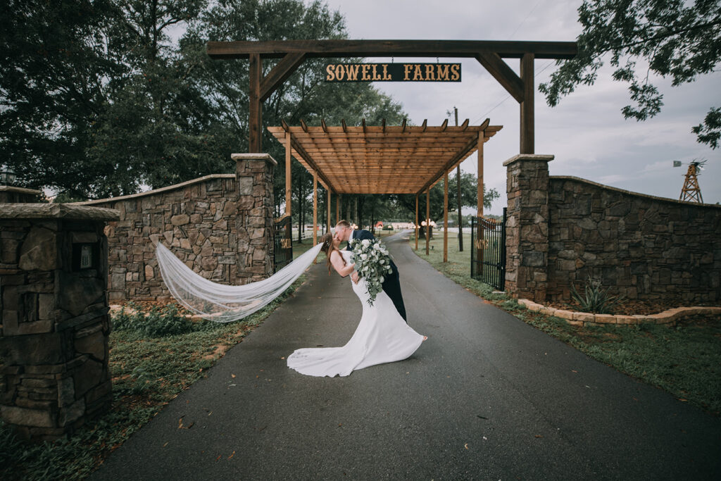 bride and groom dip kiss under the sowell farms sign