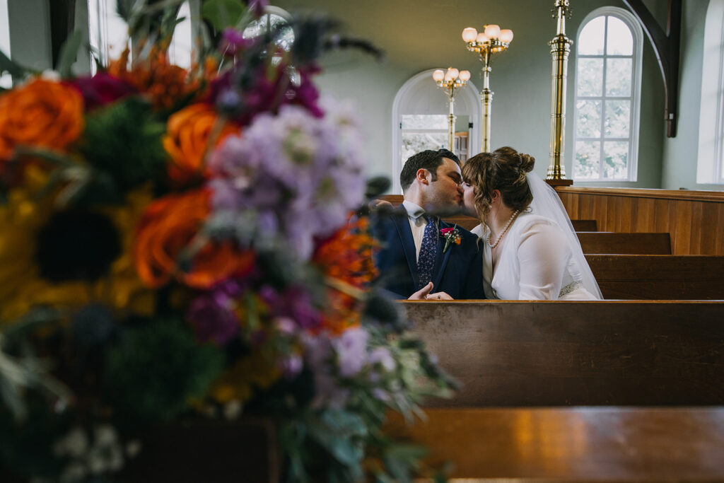 bride and groom sitting on the long benches at Old Christ Church in Pensacola, FL