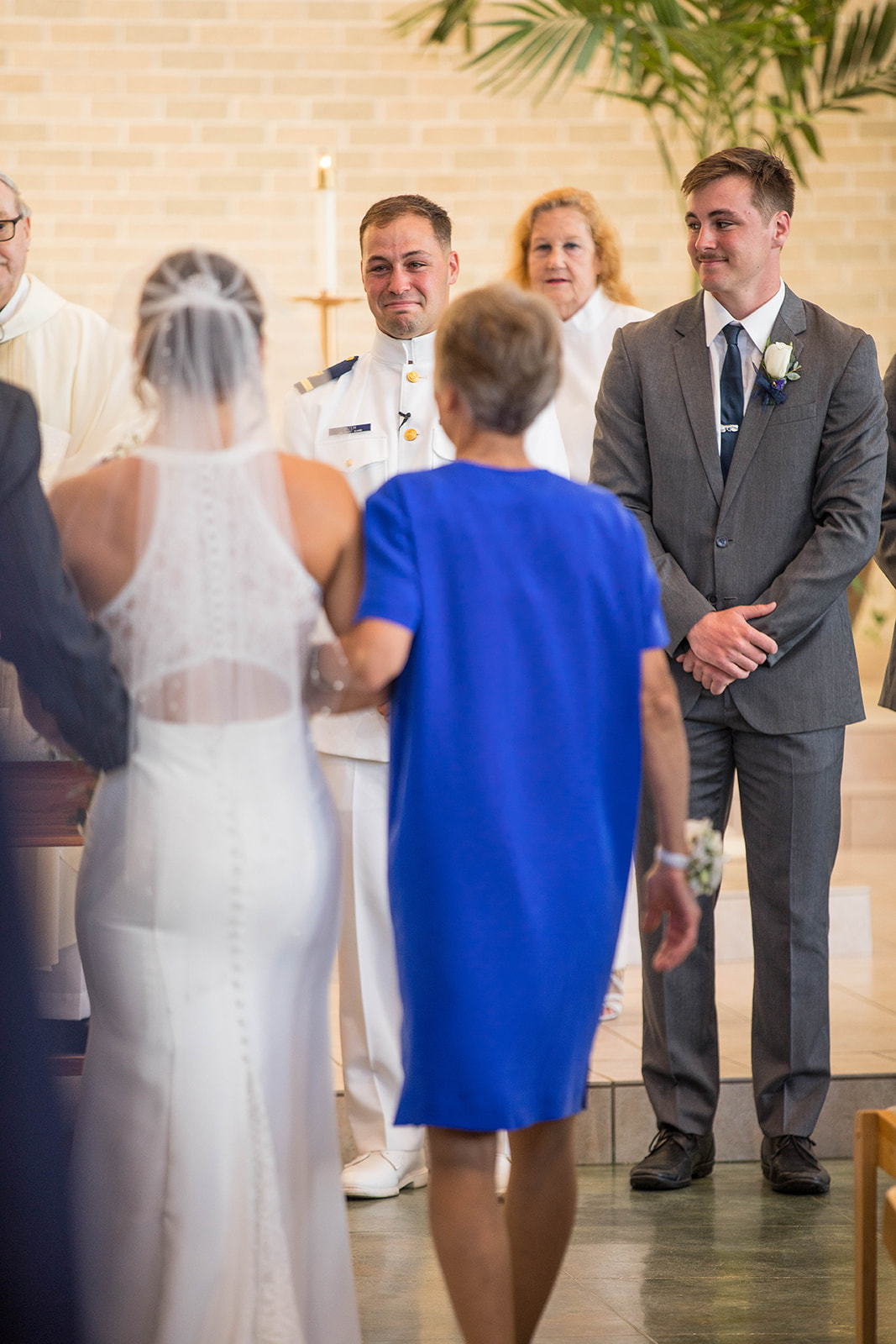 Groom in military uniform awaits his bride after he got his first look of her in her white dress walking down the aisle at their wedding in Pensacola, Florida. 