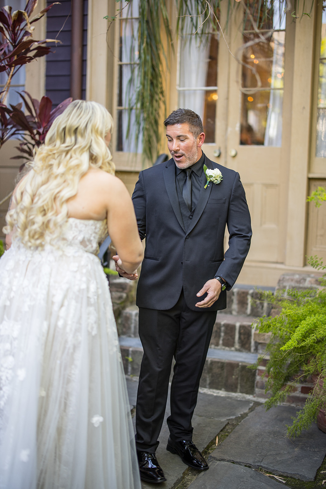 Groom in a black suit reacts to seeing his bride in her white dress at the Seraphim House in New Orleans, Louisiana. 