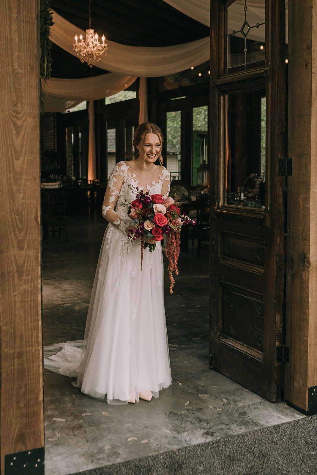 Smiles from the bride in her white dress holding her wedding bouquet as her groom sees her at their first look on their wedding day.