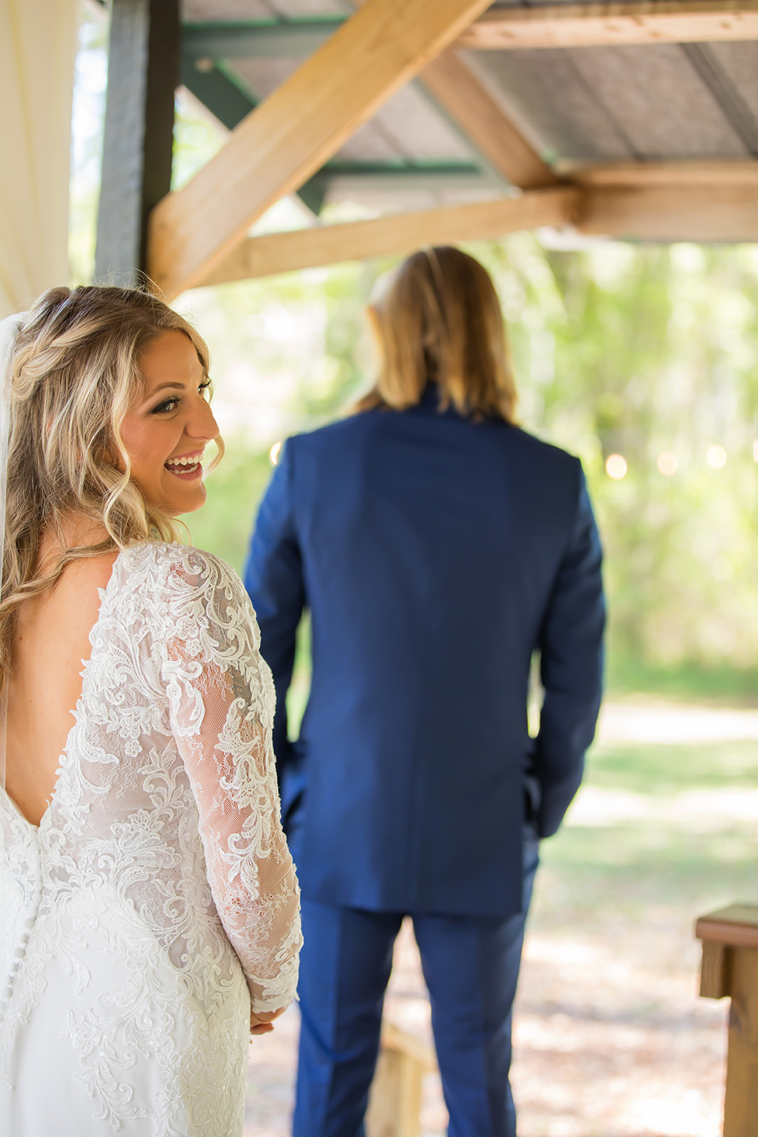 Bride in her white dress smiles as she approaches her groom for their first look.