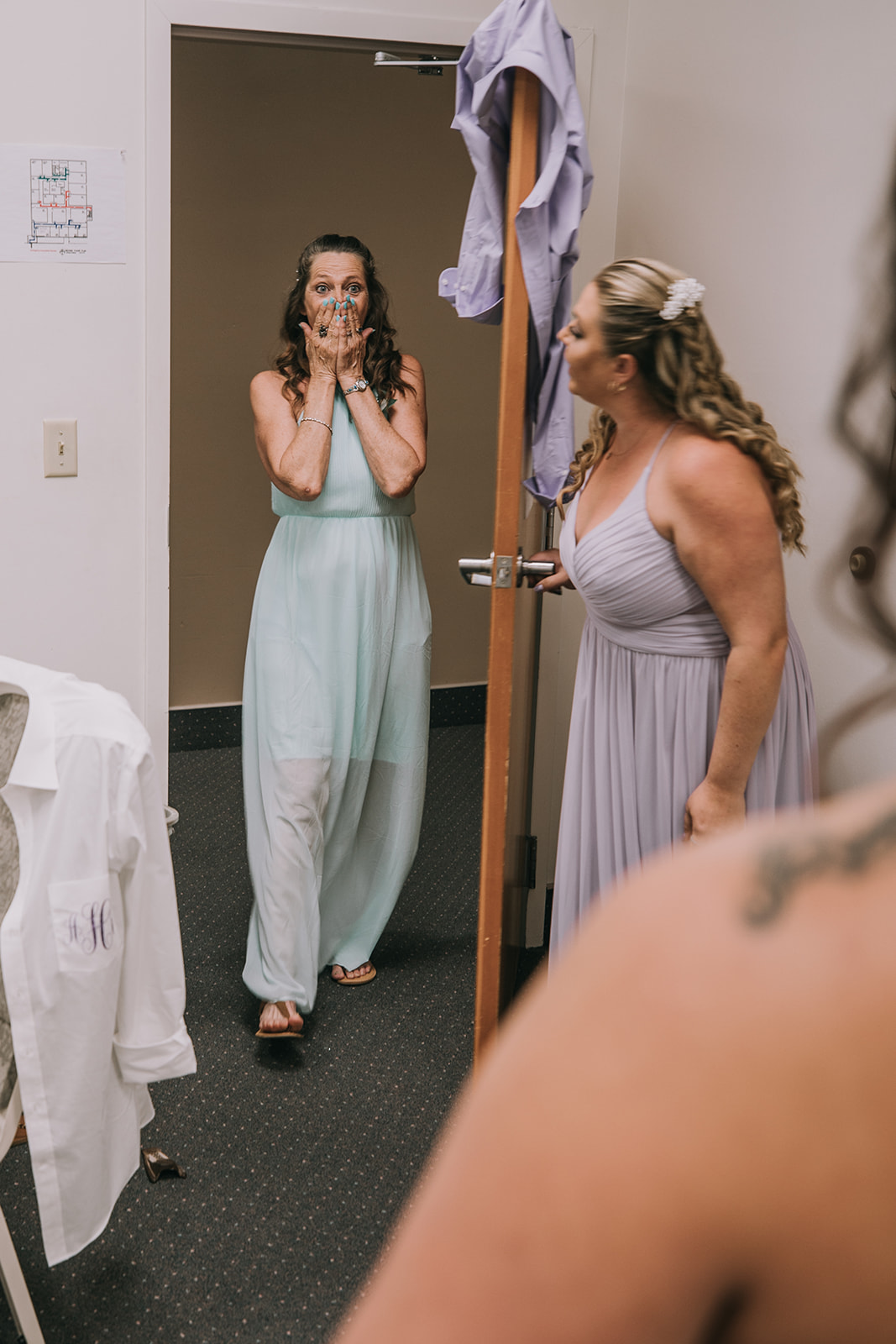 A mother in a teal dress is overwhelmed at the sight of her daughter in her wedding dress.